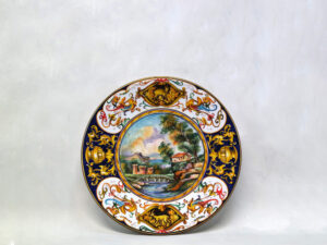 Piatto in ceramica faentina da 24,5 cm: paesaggio collinare, fiume, draghi